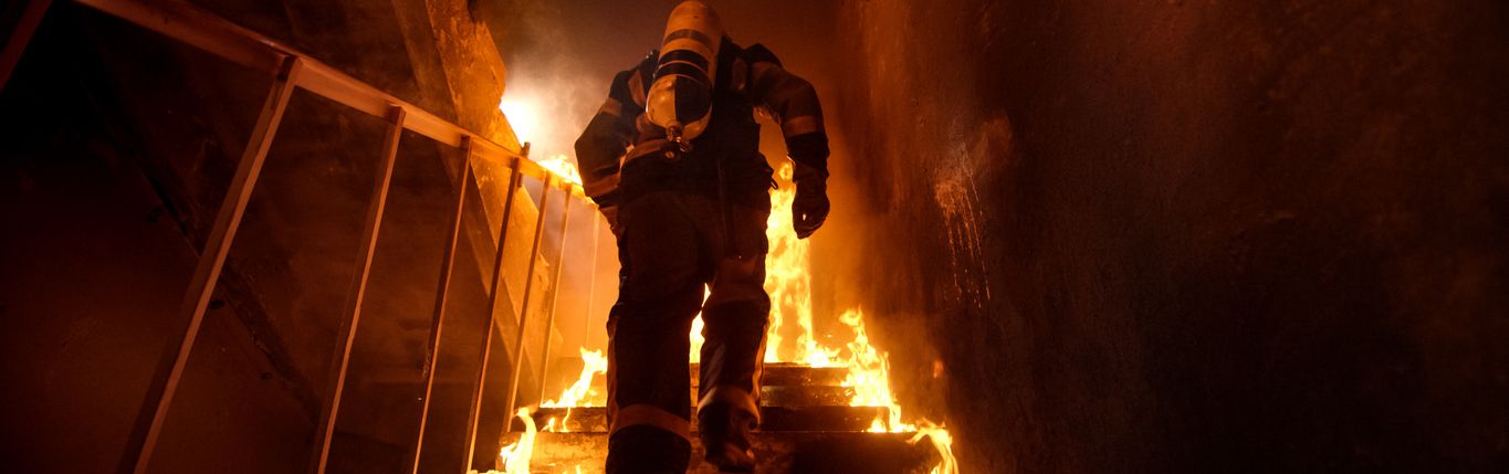 Ein Feuerwehrmann läuft durch ein brennendes Treppenhaus.