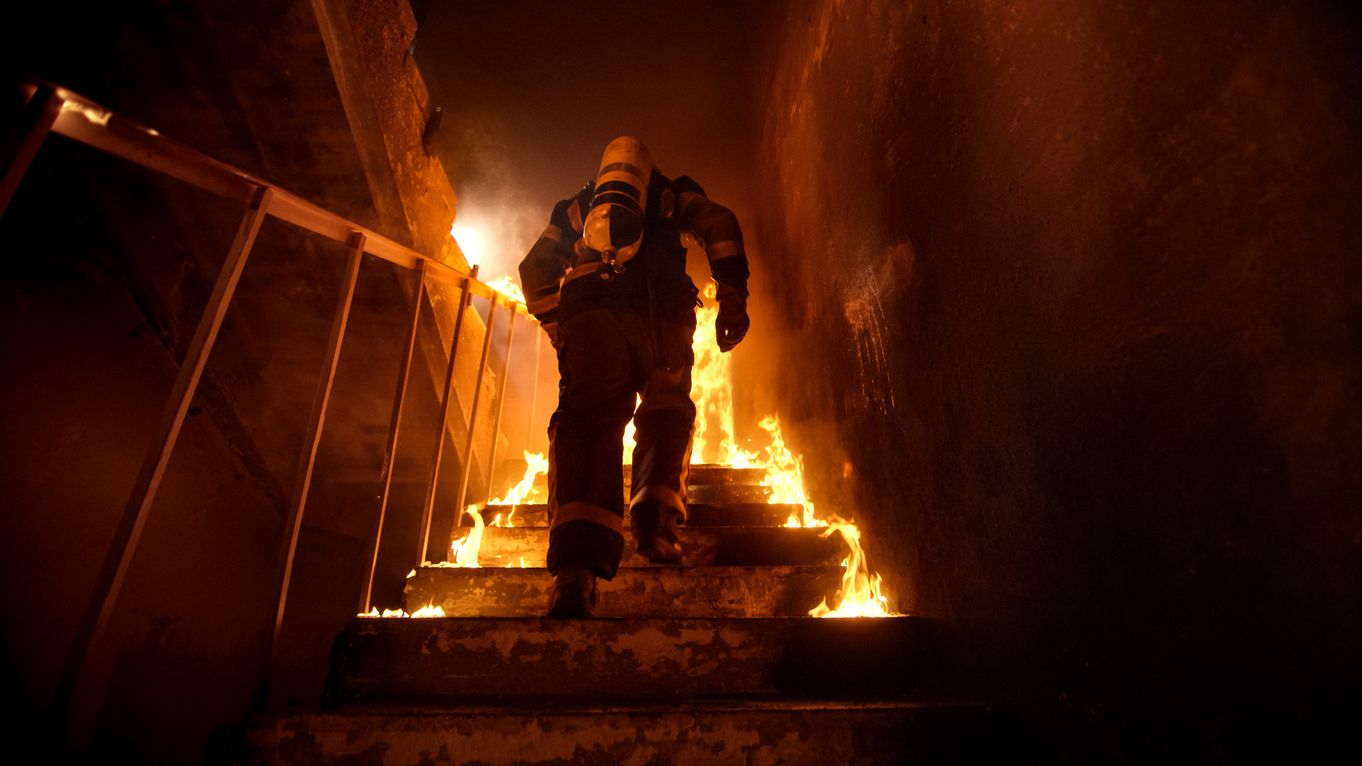 Ein Feuerwehrmann läuft durch ein brennendes Treppenhaus.