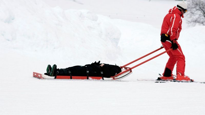 Eine verletzte Person wird von einem Angehörigen der Bergwacht auf Skiern mit einem Schlitten transportiert.